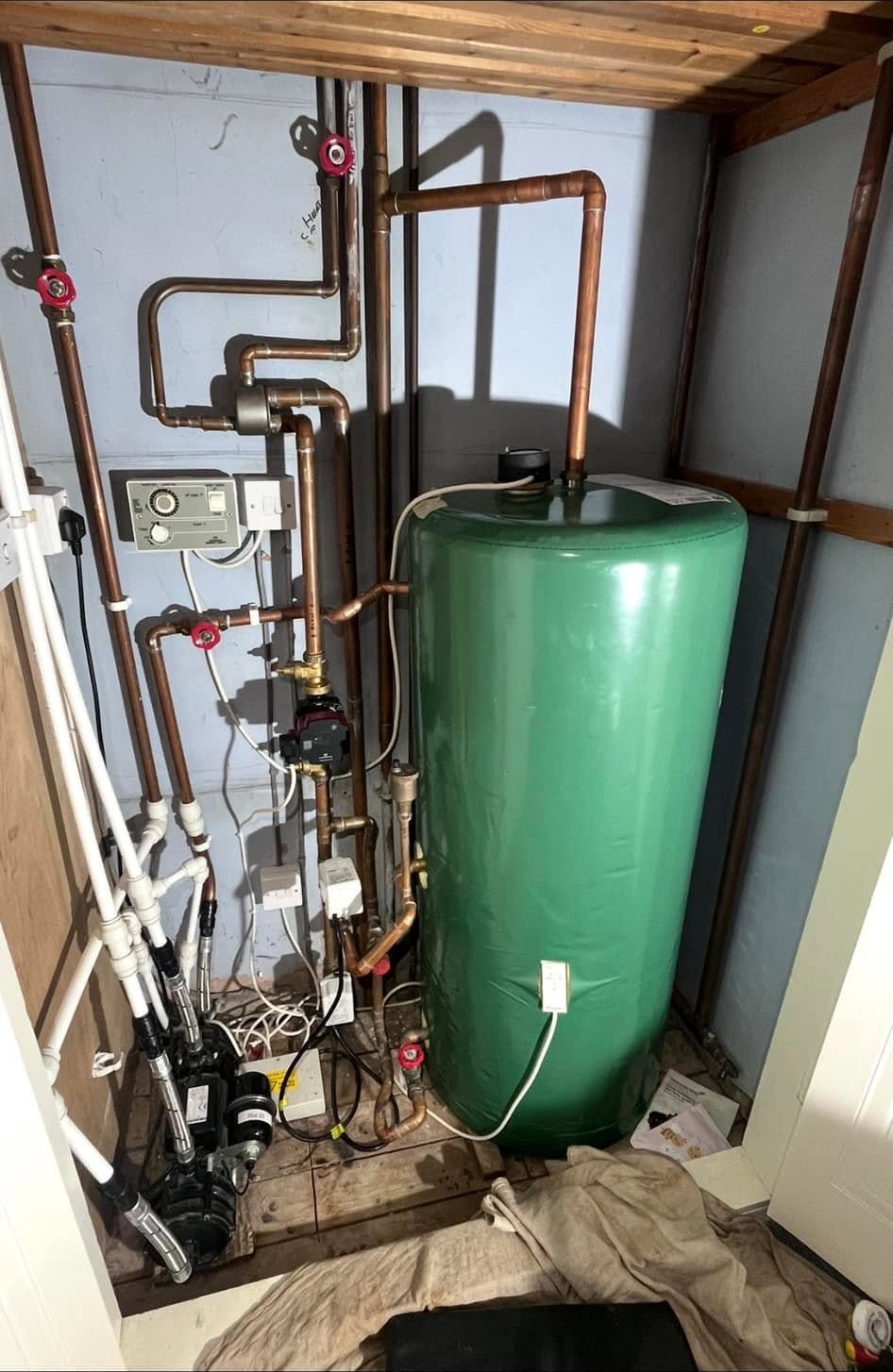 Airing cupboard before the work, with the old cylinder and pipework