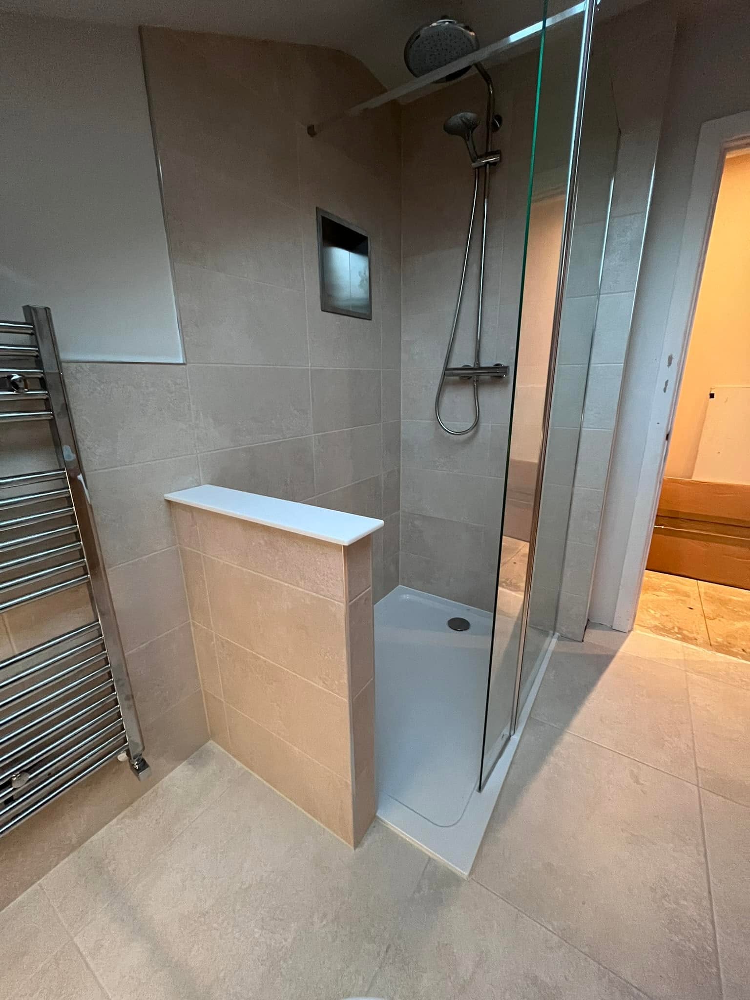 Walk-in shower room with large stone-effect tiles, glass screen and towel radiator